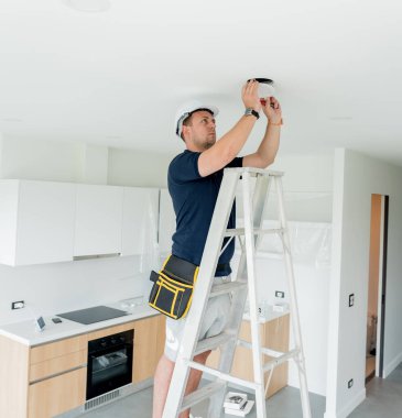 Teknisyen tavana bir LED spot ışığı yerleştiriyor.