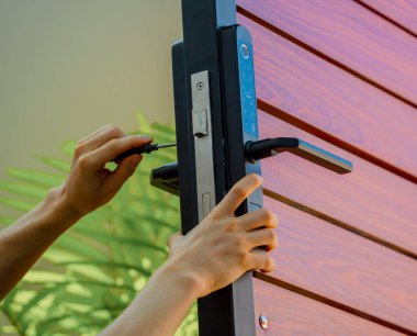 Bir teknisyen ahşap kapıya modern bir kapı kilidi takıyor..