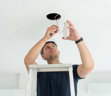 Teknisyen tavana bir LED spot ışığı yerleştiriyor.