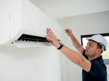 Teknisyen modern bir dairede klima sistemi temizliyor.