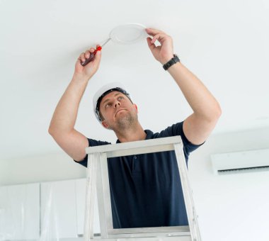 Teknisyen tavana bir LED spot ışığı yerleştiriyor.