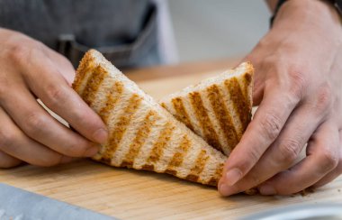 Şef ızgarada kızartılmış beyaz ekmek pişiriyor..