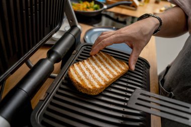 Şef ızgarada kızartılmış beyaz ekmek pişiriyor..