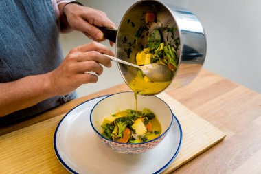 Aşçı mutfakta yeşil köri hazırlıyor otlar ve pirinçle.