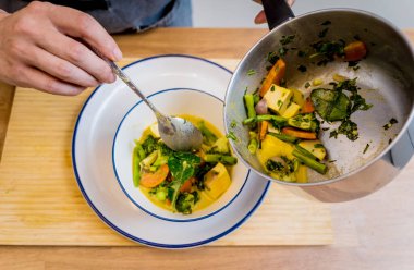 Aşçı mutfakta yeşil köri hazırlıyor otlar ve pirinçle.