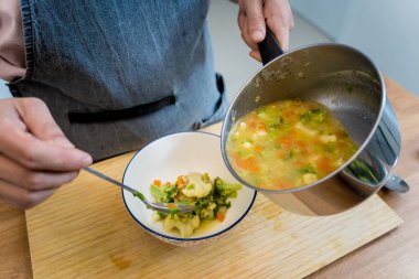 Şef mutfakta karnabahar ve brokoliyle mercimek çorbası hazırlıyor..