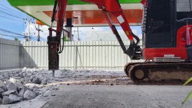 Bir kazıcı inşaat başlamadan önce beton bir asfalt katmanını yıkar.