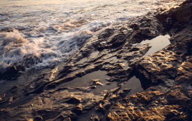 Okyanus dalgalarıyla çevrili büyük bir kaya..