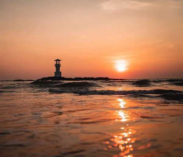 stock image A lighthouse in the ocean during a beautiful sunset.