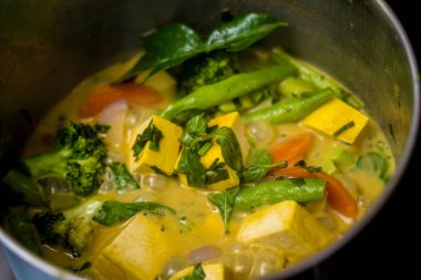 Aşçı mutfakta yeşil köri hazırlıyor otlar ve pirinçle.