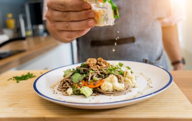 Şef mutfakta mercimekli Japon karabuğday makarnası hazırlıyor..