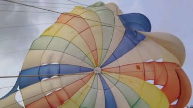 Bulutlu bir gökyüzünde uçan renkli bir paraşüt..