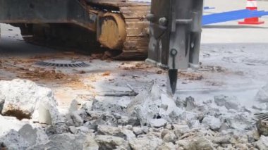 Bir kazıcı inşaat başlamadan önce beton bir asfalt katmanını yıkar.