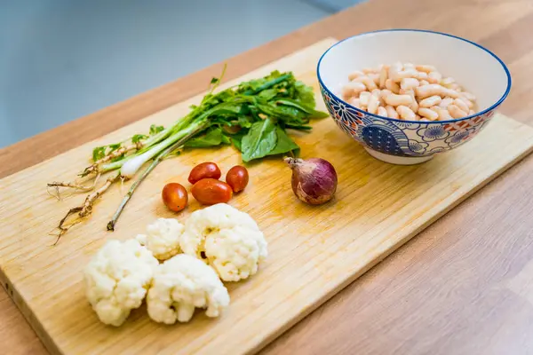 Stock image Cutting board with ingredients for preparing bean porridge with cauliflower and vegetables.