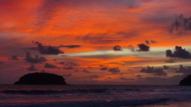Parlak gökyüzü ve parlayan renklerle okyanusun üzerindeki tropikal günbatımının çarpıcı görüntüsü.