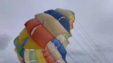 Bulutlu bir gökyüzünde uçan renkli bir paraşüt..