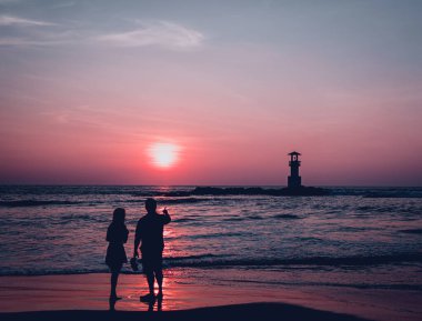 Güzel bir gün batımında okyanusta bir deniz feneri.