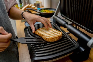 Şef ızgarada kızartılmış beyaz ekmek pişiriyor..