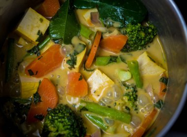 Aşçı mutfakta yeşil köri hazırlıyor otlar ve pirinçle.