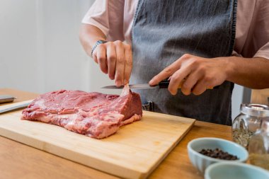 Şef mutfakta, ev yapımı elektrikli ızgarada biftekler için çiğ biftek hazırlıyor..