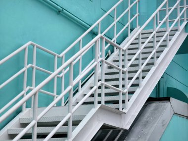 Gökyüzüne ve bulutlara karşı mavi binaya giden metal merdivenler.