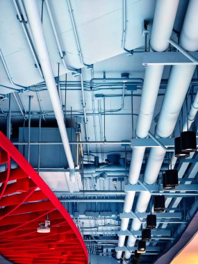 Endüstriyel binada havalandırma boruları ve ışıkları olan bir tavan..