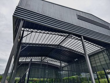 Bulutlu gökyüzüne karşı metal çatılı büyük bir bina..