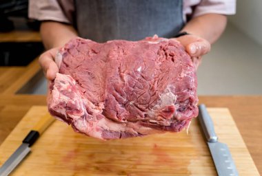 Şef mutfakta, ev yapımı elektrikli ızgarada biftekler için çiğ biftek hazırlıyor..