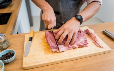 Şef mutfakta, ev yapımı elektrikli ızgarada biftekler için çiğ biftek hazırlıyor..