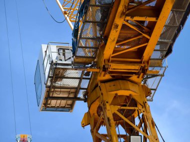 Büyük sarı bir vinç parlak mavi bir gökyüzüne karşı duruyor..