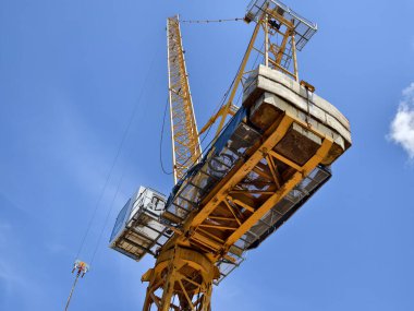 Büyük sarı bir vinç parlak mavi bir gökyüzüne karşı duruyor..