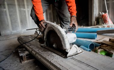 Büyük bir beton parçası kesmek için dairesel testere kullanan bir inşaatçı..