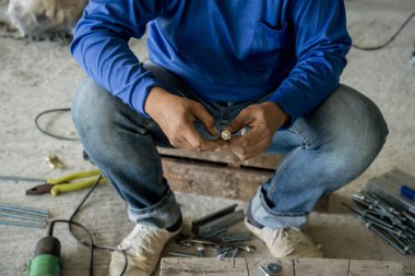 Bir inşaatçı tahta bir palette vida ve fındıkla çalışır..