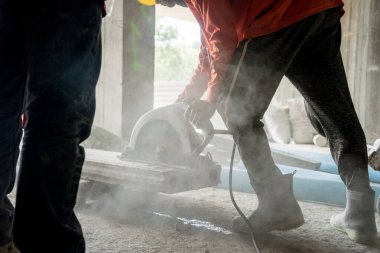 Büyük bir beton parçası kesmek için dairesel testere kullanan bir inşaatçı..