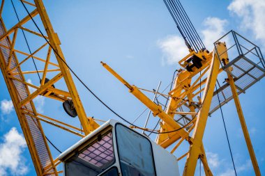 Büyük sarı bir vinç parlak mavi bir gökyüzüne karşı duruyor..