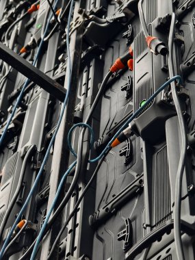 Bir grup elektrik kablosu ve konnektörler kurşun bir panelden sarkıyor..