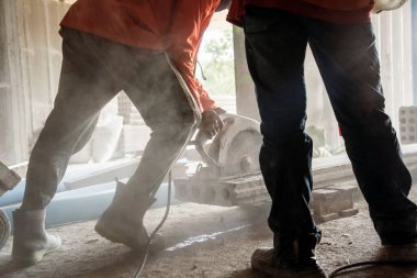 Büyük bir beton parçası kesmek için dairesel testere kullanan bir inşaatçı..