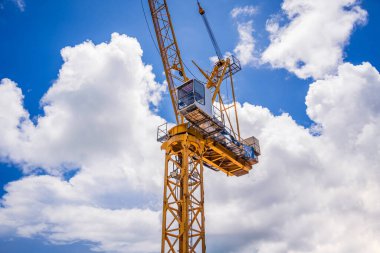 Büyük sarı bir vinç parlak mavi bir gökyüzüne karşı duruyor..