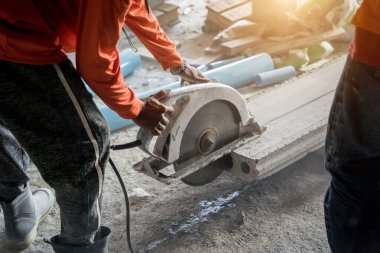 Büyük bir beton parçası kesmek için dairesel testere kullanan bir inşaatçı..