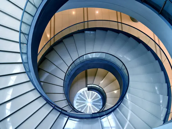 stock image A beautifully designed spiral staircase in a modern building with glass railing.