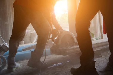 Büyük bir beton parçası kesmek için dairesel testere kullanan bir inşaatçı..