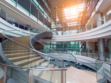 Modern bir binada cam parmaklıklı güzel tasarlanmış spiral bir merdiven..