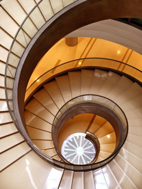Modern bir binada cam parmaklıklı güzel tasarlanmış spiral bir merdiven..