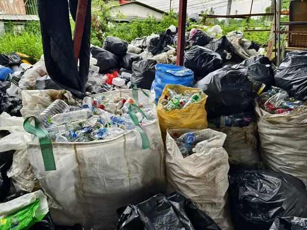 Bir poşetin içinde büyük bir plastik şişe ve kutu yığını var..