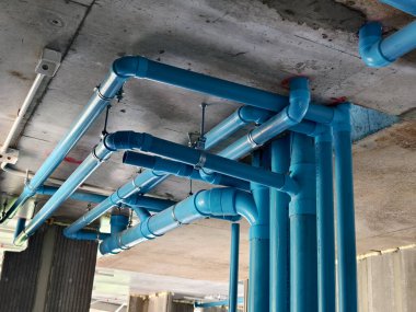 Beton bir duvara bağlı parlak mavi borular..