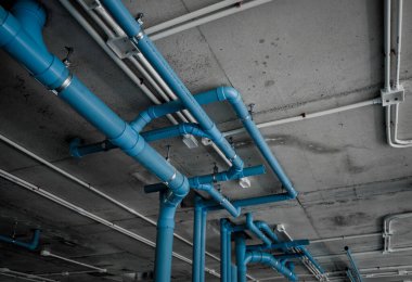 Beton bir duvara bağlı parlak mavi borular..