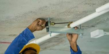 Sert şapkalı bir adam düz bir aletle çalışıyor..