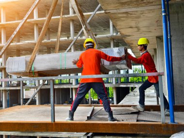 İnşaat halindeki bir binada işçiler vinçten levha alıyorlar..