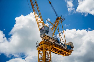 Büyük sarı bir vinç parlak mavi bir gökyüzüne karşı duruyor..