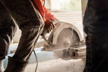 Büyük bir beton parçası kesmek için dairesel testere kullanan bir inşaatçı..